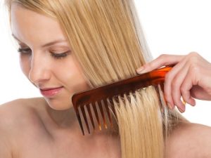 mujer rubia peinándose con peine de púas